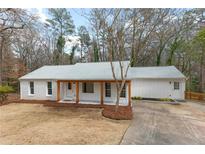 Charming home with a wood-columned porch and freshly painted white brick and siding at 60 Willow Springs Ln, Roswell, GA 30075