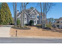 Stately gray two-story home featuring a manicured lawn and mature trees at 6305 Deerwoods Trl, Alpharetta, GA 30005