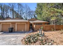 Charming tan home with attached garages, set amidst trees and landscape at 841 Lake Hollow Sw Blvd, Marietta, GA 30064