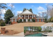 Stately red brick home featuring white columns, black shutters, a well manicured yard, and a custom in ground pool at 1380 Tennis Court Pl, Roswell, GA 30075