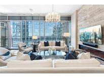 Bright living room with city views, modern chandelier, and stone accent wall with a fireplace at 1065 Peachtree Ne St # 3105, Atlanta, GA 30309
