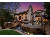 Outdoor living with a stunning waterfall pool, spa, and fire bowls set against a beautiful home exterior at twilight at 1352 Middlesex Ne Ave, Atlanta, GA 30306