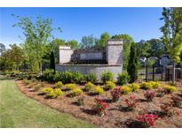 Stone entrance to Wards Crossing with manicured landscaping and colorful flowering shrubs at 133 Ward'S Crossing Way # 18, Johns Creek, GA 30022