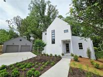 Modern exterior with white siding, black-framed windows, manicured landscaping, and two-car garage at 145 Cedarwood Ln, Roswell, GA 30075