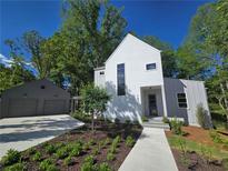 Beautiful modern farmhouse with white siding, black trim, and a lush landscaped front yard at 145 Cedarwood Ln, Roswell, GA 30075