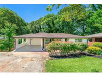Charming ranch-style home with lush front yard landscaping and a covered carport on a sunny day at 2682 Miriam Ln, Decatur, GA 30032