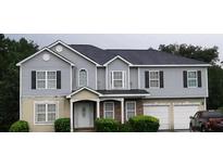 Two-story home featuring gray siding, black shutters, and a two-car garage, set against a lush green backdrop at 3551 Northgate Cv, Ellenwood, GA 30294