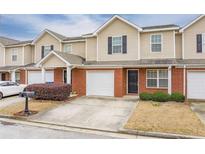 Charming townhome with brick and tan siding, showcasing an attached garage and well-maintained landscaping at 453 Tara Commons Cir, Loganville, GA 30052