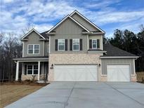 New two-story home featuring brick and gray siding, a three-car garage, and a well-manicured lawn at 897 Porches Way, Dacula, GA 30019