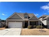 Charming home featuring brick and siding, a two-car garage, and a well-manicured front yard at 4030 Rockcap Cv, Buford, GA 30519