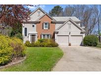 Charming two-story home featuring a brick facade, two-car garage, and a well-manicured lawn at 7335 Treyland Ct, Cumming, GA 30041