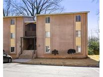 Apartment complex featuring tan stucco siding, traditional windows, and a parking area at 2388 Lawrenceville Hwy # M, Decatur, GA 30033