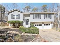 Split-level home featuring neutral siding, black shutters, and a well-maintained front yard with mature landscaping at 8740 Jenkins Rd, Winston, GA 30187