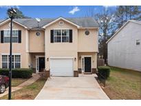 Two-story townhome features a one-car garage, well-kept lawn, and a neatly paved driveway at 2322 Coach Way, Jonesboro, GA 30236