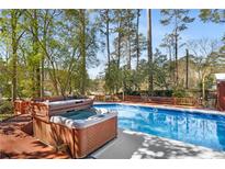 Inviting in-ground pool and hot tub surrounded by a wooden deck and lush trees, perfect for relaxation at 1175 Kingsley Ne Cir, Atlanta, GA 30324
