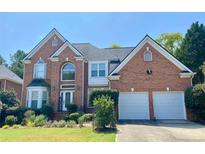 Charming two-story brick home with attached two-car garage and well-manicured front lawn at 10890 Regal Forest Dr, Suwanee, GA 30024