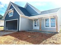Charming home exterior with two-car garage, gray siding, and a covered front porch with wooden support beams at 33 Cambridge Ln, Dallas, GA 30157