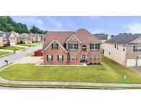 Inviting two-story brick home featuring a manicured lawn, arched entryway, and symmetrical window placement at 106 Dustin Dr, Stockbridge, GA 30281