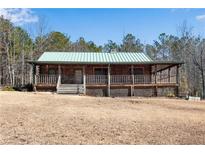 Charming log cabin with a welcoming front porch and a green metal roof at 5256 Kilroy Ln, Douglasville, GA 30135