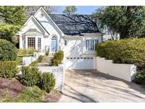 Charming white brick home featuring a blue front door, well-manicured landscaping and attached garage at 1212 University Ne Dr, Atlanta, GA 30306