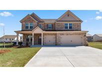 Inviting two-story brick home featuring a spacious three-car garage and manicured lawn at 2396 Cadenza Cir, Dacula, GA 30019