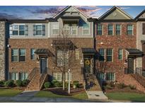 Charming townhome featuring a brick facade, individual entrances, and manicured landscaping at 4478 Dunblane Ave, Sugar Hill, GA 30518