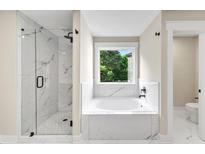 Elegant bathroom featuring a glass shower and a luxurious soaking tub with marble tile surround at 703 Sierra Ct, Canton, GA 30114