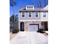 Charming townhome featuring a stone-accented facade, gray siding, and a convenient two-car garage at 2256 Triple Crown Ln, Lithonia, GA 30058