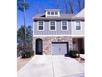 Charming townhome featuring a stone facade, gray siding, and an attached two-car garage with a private entrance at 2256 Triple Crown Ln, Lithonia, GA 30058