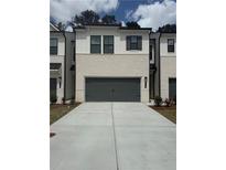 Charming townhome showcasing a 2-car garage and neutral-toned brick exterior, complemented by modern design elements at 984 Sutherland Ln (Lot 31), Lawrenceville, GA 30043