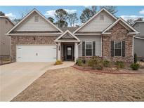 Charming single-Gathering home features a brick and stone facade, a well-maintained lawn, and an attached two-car garage at 247 Oaklawn Park, Dacula, GA 30019