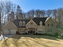 Stately brick and stone home with a manicured lawn, mature trees, and attached two car garage at 3258 Teton Se Dr, Atlanta, GA 30339