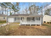 Charming gray home featuring a welcoming front porch with white railings and black shutters surrounded by mature trees at 1389 Ling Dr, Austell, GA 30168
