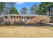 Charming brick home featuring a well-manicured front yard with mature trees and a bright blue front door at 2781 Hollywood Dr, Decatur, GA 30033