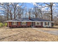 Charming brick home featuring a dark roof, chimney, and a well-maintained lawn surrounded by mature trees at 35 Adair Dr, Marietta, GA 30066