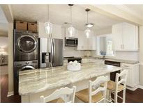 Bright kitchen features stainless appliances, stacked washer and dryer, and a marble countertop island with seating at 168 Maribeau Nw Sq, Atlanta, GA 30327