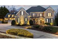 Charming two-story home with stone and beige siding, a large driveway, lush landscaping, and a welcoming front porch at 2146 Wolbert Trl, Marietta, GA 30062