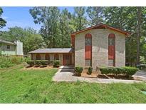 Charming brick home with a well-manicured front lawn and mature trees at 1172 Martin Nash Sw Rd, Lilburn, GA 30047