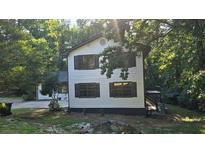 Charming two-story home with white siding, black shutters, and a lush green lawn at 409 Arbor Ridge Dr, Stone Mountain, GA 30087