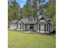 Charming one-story home featuring white siding, black trim, a covered porch, and an attached two car garage at 4902 Cedar Se Ct, Conyers, GA 30094