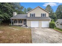 Two-story home with a traditional facade, featuring a two-car garage and a well-maintained lawn at 8740 Parliament Pl, Jonesboro, GA 30238