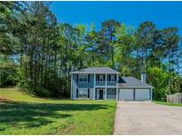 Charming two-story home features a double garage, front porch, well-manicured lawn, and beautiful landscaping at 3534 S Portsmouth Cir, Lithonia, GA 30038