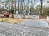 Charming single-Gathering home with gray siding, dormer windows, and a gravel driveway at 806 Longfellow Ct, Stone Mountain, GA 30088