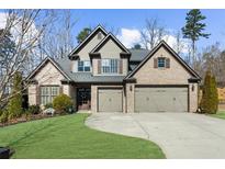 Inviting brick home with a manicured lawn and a three-car garage, perfect for a growing Gathering at 1605 Camden Cove Dr, Cumming, GA 30040