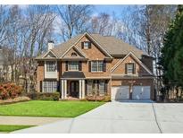 Beautiful two-story brick home with a manicured lawn, two-car garage, black shutters, and mature trees at 1211 Promontory Path, Marietta, GA 30062