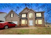 Charming two-story brick home with attached garage, manicured lawn, and inviting front entrance at 1224 Crossbow Ter, Hampton, GA 30228