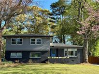 Charming two-story home with a well-manicured lawn, blue door, and beautiful mature trees at 2316 Miriam Ln, Decatur, GA 30032