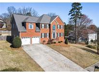 Charming two-story red brick home with a well-manicured front yard and attached two-car garage at 3176 Crestmont Nw Way, Kennesaw, GA 30152