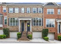 Charming brick townhome with well-manicured landscaping, covered entryway, and attached garages at 1555 Mosaic Way # 1555, Smyrna, GA 30080