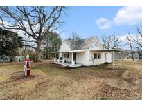 Charming white home featuring a covered porch, a vintage gas pump, and a spacious yard at 2885 Camp Mitchell Rd, Loganville, GA 30052